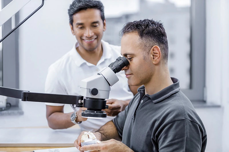 Zahntechnikermeister Ahmet Kadioglu und Dr. Dennis Daniels am Labor-Mikroskop im hauseigenen Meisterlabor der Nova-Smile MVZ GmbH in Düsseldorf